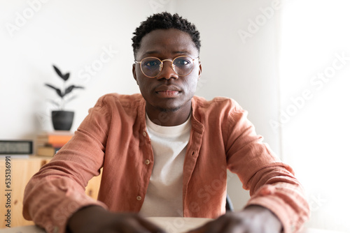 Black young man looking at camera with serious expression during video call.