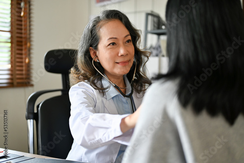 A professional senior Asian female doctor cardiologist checks up, using a stethoscope