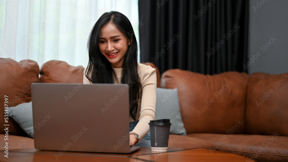 Gorgeous Asian female freelancer or businesswoman working from home, using laptop Gorgeous Asian female freelancer or businesswoman working from home, using laptop