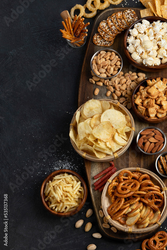 Fotografie Assortment of salty snacks on dark background.