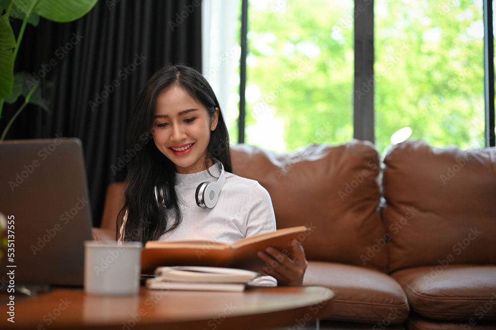 Charming Asian young female reading a book at home. Charming Asian young female reading a book at home.