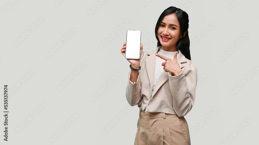 Attractive Asian female showing smartphone mockup, standing isolated over grey background. Attractive Asian female showing smartphone mockup, standing isolated over grey background.