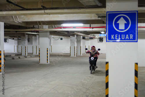 Exit sign symbol in basement with biker background. Underground parking garage. Exit sign on the driveway in parking garage. Keluar photo