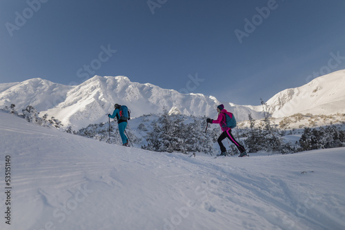 Low angle view of ski touring couple hiking up in mountains.