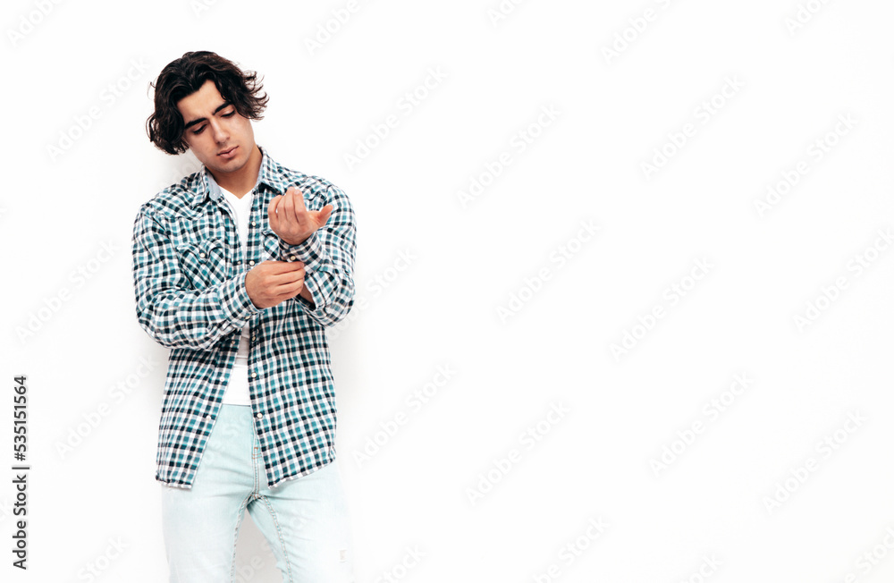 Portrait of handsome confident model. Sexy stylish man dressed in checkered shirt and jeans. Fashion hipster male posing near white wall in studio. Isolated Portrait of handsome confident model. Sexy stylish man dressed in checkered shirt and jeans. Fashion hipster male posing near white wall in studio. Isolated
