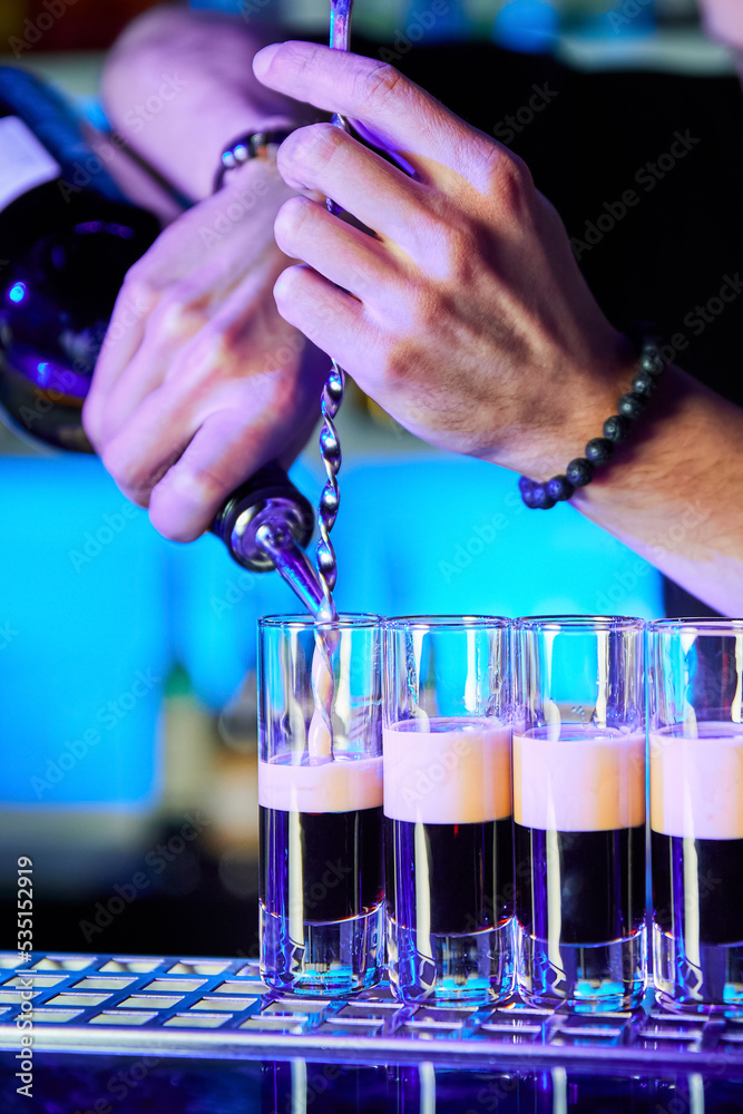 Bartender prepares alcoholic shots on bar counter