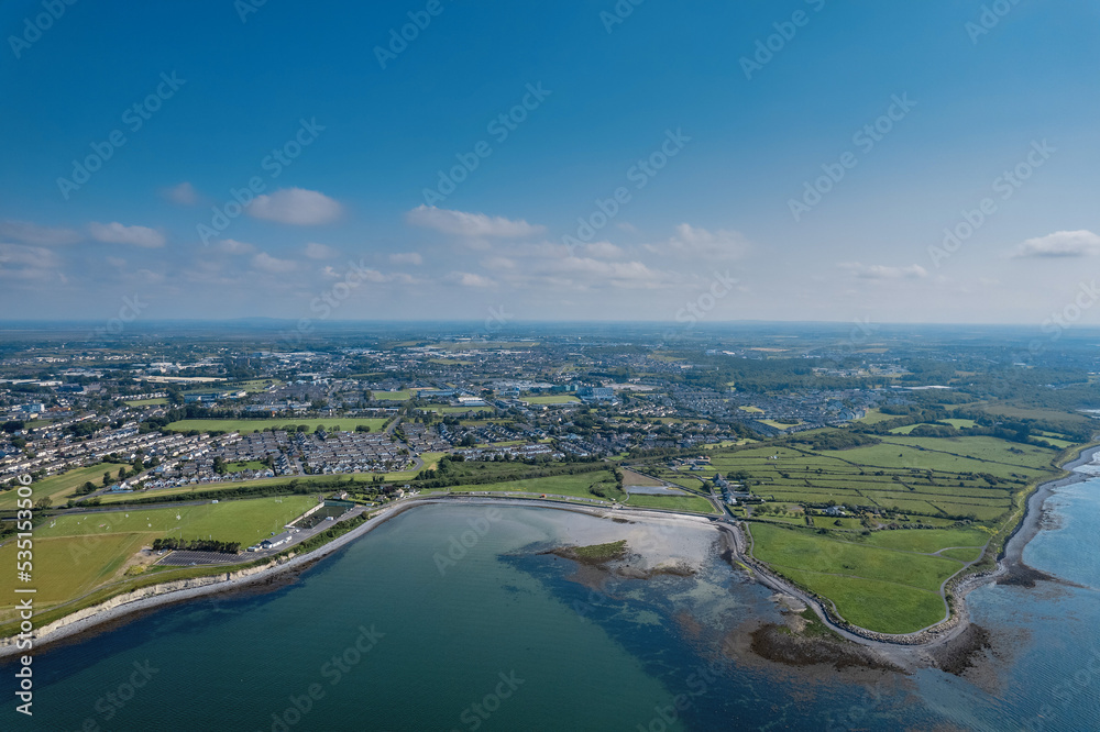 Aerial view on Ballyloughane Strand in Galway city, Ireland. High tide. Blue cloudy sky and ocean water. Popular area with amazing view and footpaths for walk close to Renmore residential area