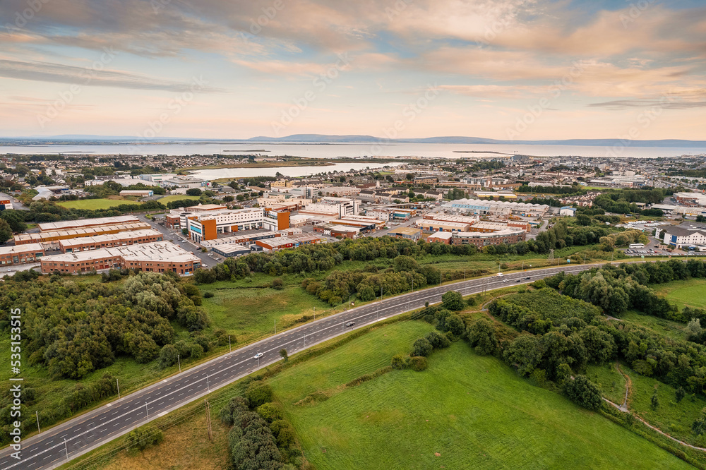 Aerial view on a city residential area with houses and park and highway. Galway, Ireland. Blue cloudy sky. High density urban land.