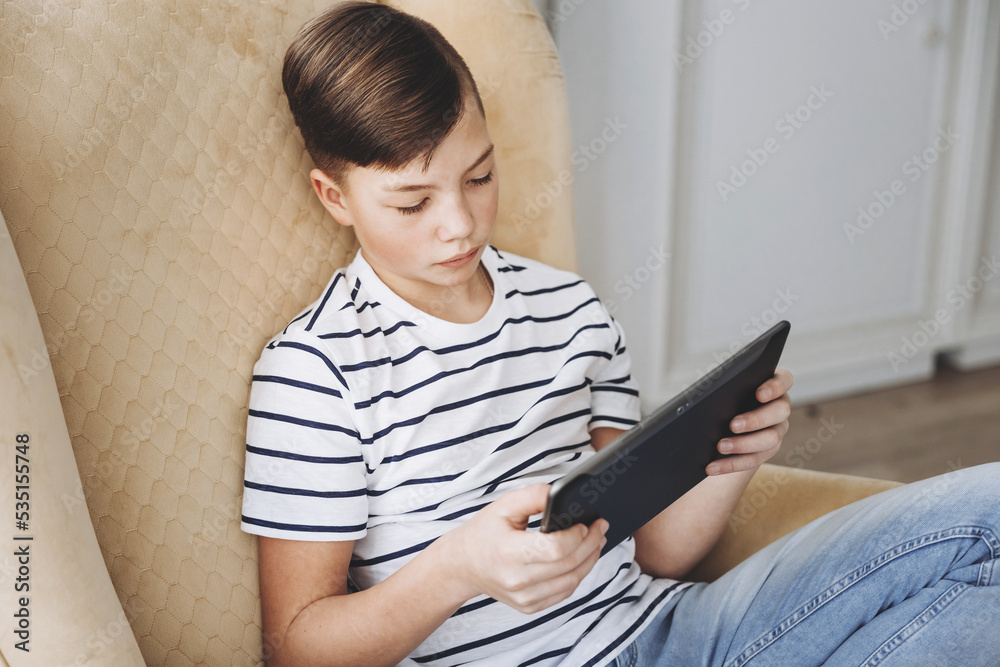 Teenage boy using tablet having video chat on internet online at home. Child watching movie, playing video game. Social media concept. Online education. Distance learning Teenage boy using tablet having video chat on internet online at home. Child watching movie, playing video game. Social media concept. Online education. Distance learning