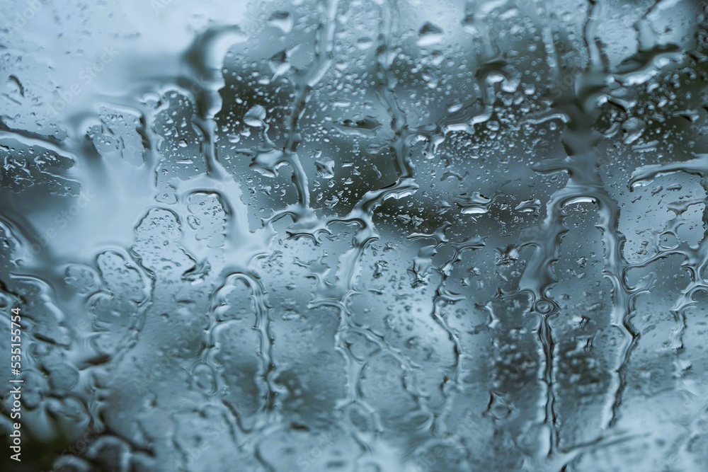 Blurred photo. Heavy rain, water pouring down the windshield of the car. Blurred photo. Heavy rain, water pouring down the windshield of the car.