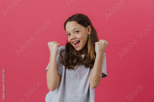 White preteen girl wearing t-shirt laughing and making winner gesture photo