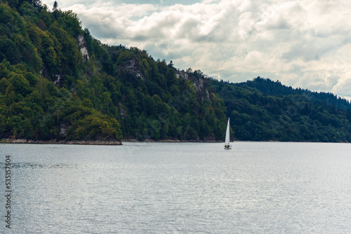 Fototapeta Naklejka Na Ścianę i Meble -  A lonely sailboat on a lake surrounded by mountain rocks. Czorsztyn, Poland