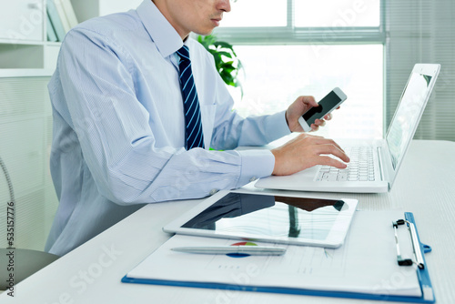 Businessman in office using laptop, tablet and smart phone on the desk