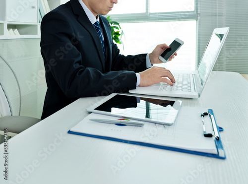 Businessman in office using laptop, tablet and smart phone on the desk
