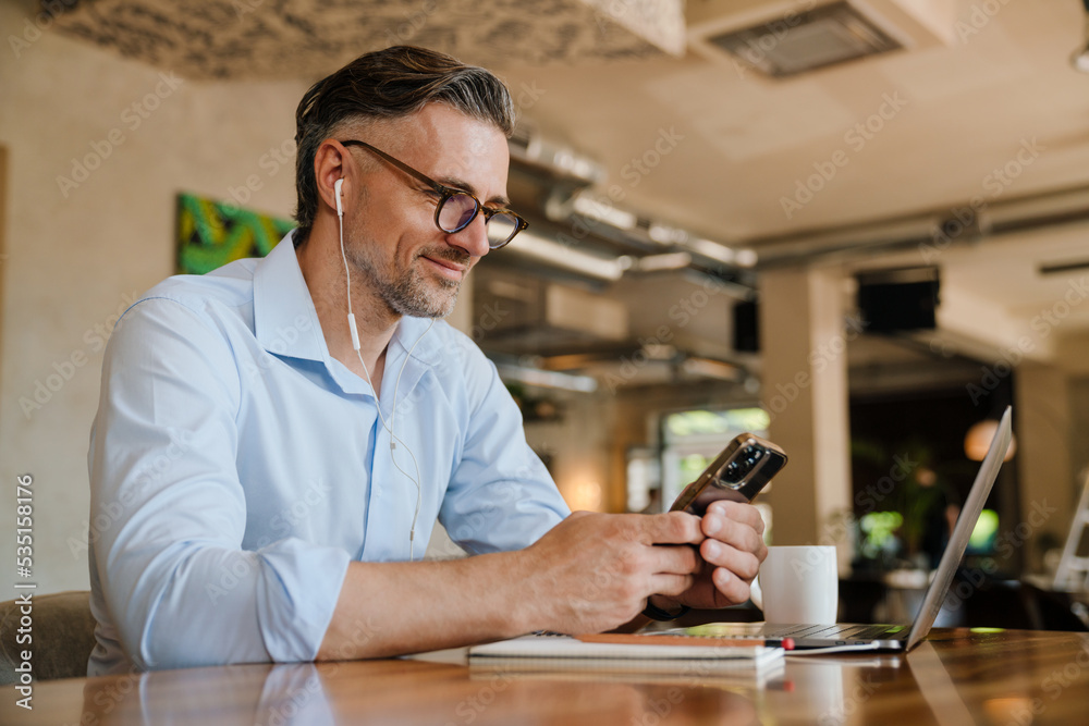 European grey man using mobile phone while working at office
