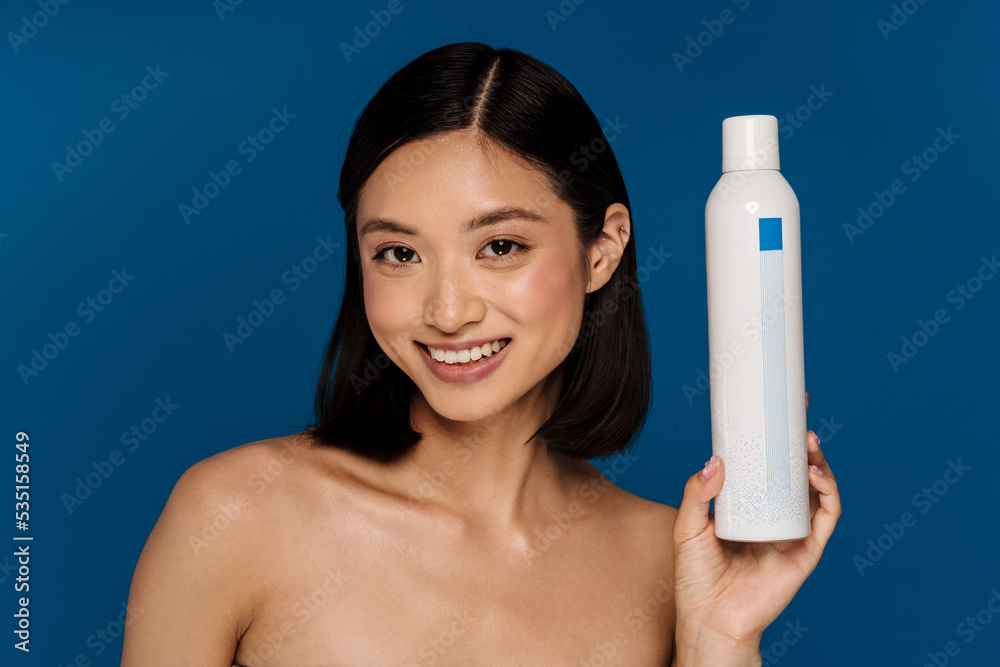 Young beautiful happy smiling asian woman holding cosmetic care product Young beautiful happy smiling asian woman holding cosmetic care product