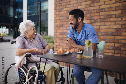 Caregiver having breakfast with his client at cafe.