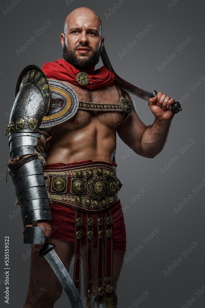 Portrait of ancient gladiator with bare torso posing with dual swords against grey background. Portrait of ancient gladiator with bare torso posing with dual swords against grey background.