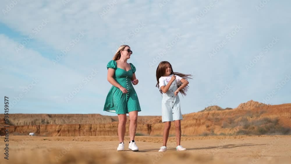 Mom and daughter are dancing on outdoors. Funny family dances. A beautiful woman in a green dress dances with a child. Mom and daughter are dancing on outdoors. Funny family dances. A beautiful woman in a green dress dances with a child.