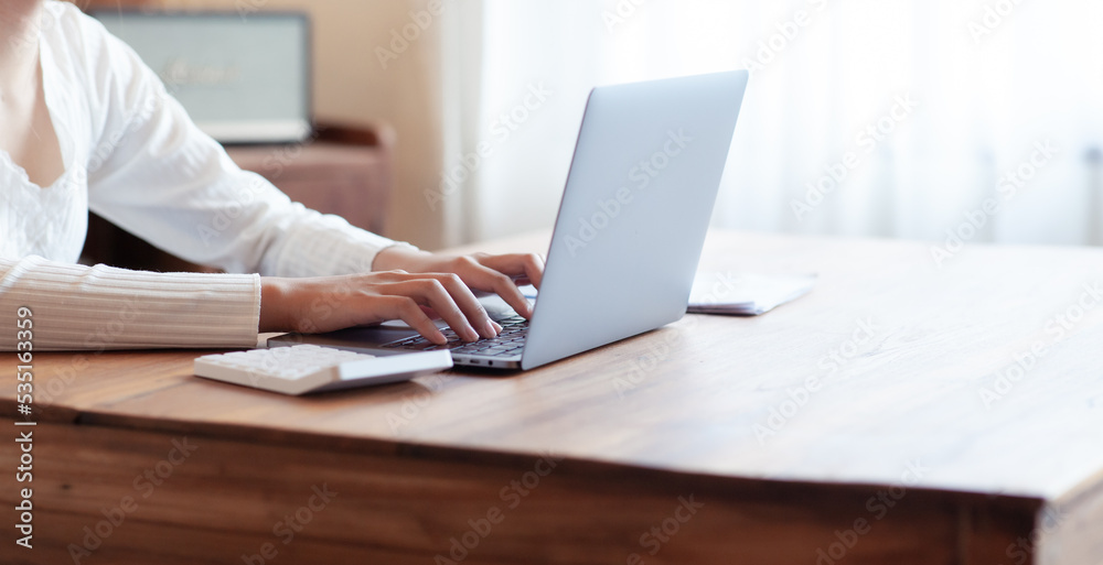 business woman drinking coffee and working on wooden table at home Using a laptop and computer to assess and analyze the economy to invest successfully in his own business, business ideas.