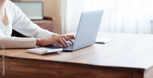 business woman drinking coffee and working on wooden table at home Using a laptop and computer to assess and analyze the economy to invest successfully in his own business  business ideas.
