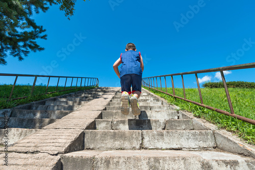 Rear view of young boy climbs up on staircase