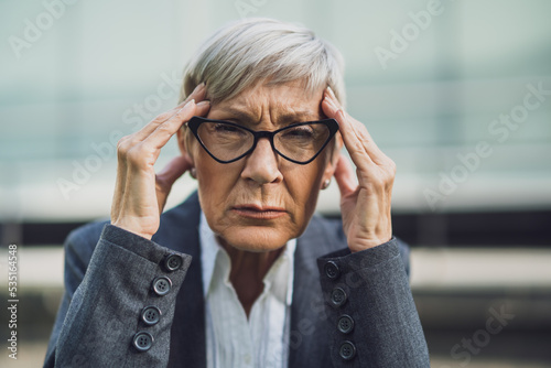 Close up portrait of senior businesswoman who is overworked and having headache.