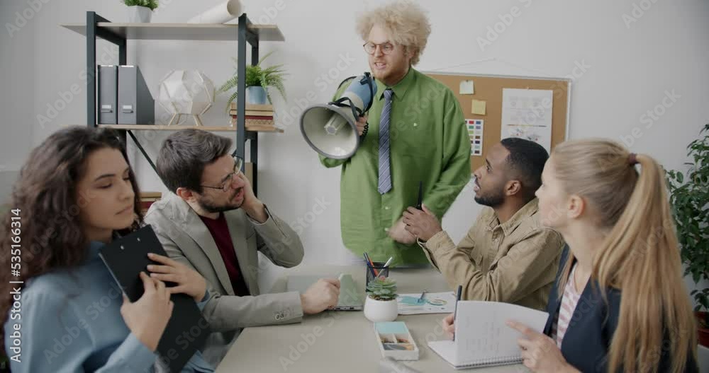 Abusive crazy boss is yelling at scared employees during meeting using loudspeaker blaming subordinates for bad work. People and workplace concept.