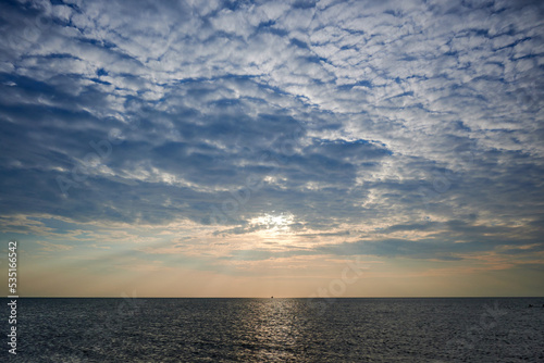 ship for fishing at horizon between clouds, light and sea
