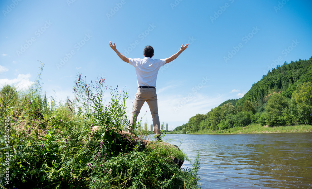 Happy young man with raised arms at lakeside Happy young man with raised arms at lakeside