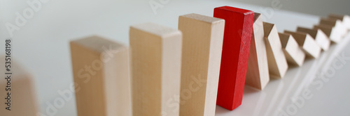 Bild auf Leinwand One red wooden block stop other ones from falling like dominoes, domino effect