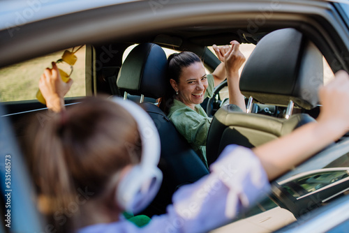 Young mother and her daughter having fun in their electric car. photo