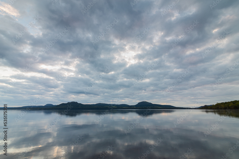 灰色の曇り空を湖面に反射する静かな湖。北海道の屈斜路湖