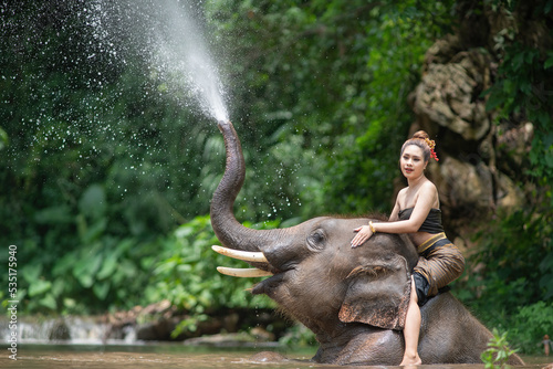 Thai Lanna women Riding an elephant in a stream, Chiang Mai, Thailand