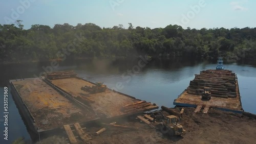 Loading barges with logs from the Amazon rainforest to transport - aerial flyover photo