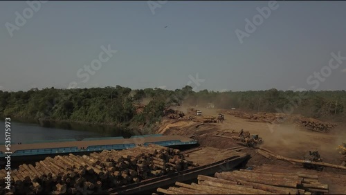 Deforestation of the Amazon rainforest: stacking logs on barges for transport - aerial flyover photo
