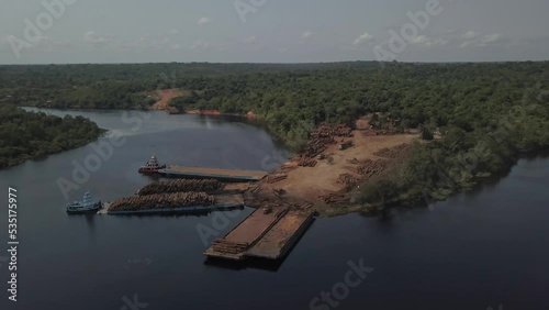 Climate change and deforestation: loading logs from the Amazon rainforest on barges for transport - aerial flyover photo