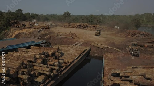 Tractor loaders stacking logs from the Amazon rainforest onto barges - aerial parallax photo