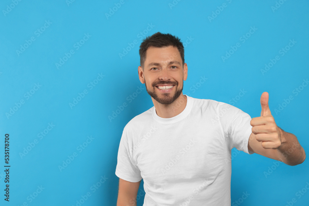 Man showing thumb up on light blue background, space for text Man showing thumb up on light blue background, space for text