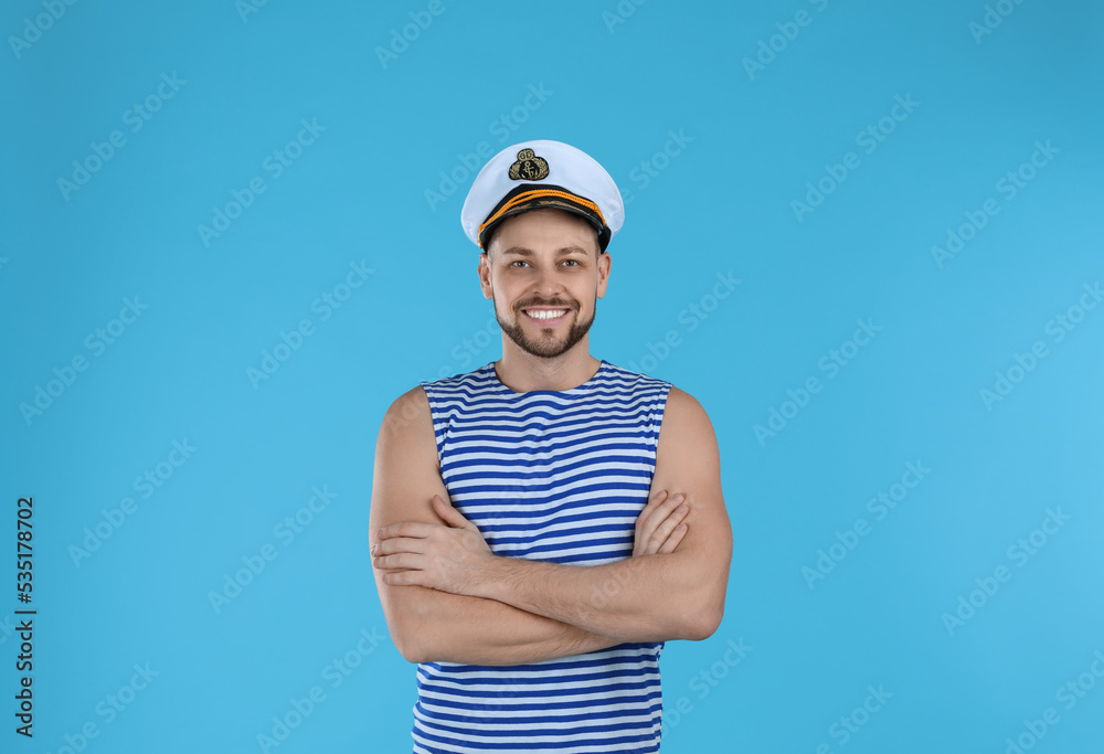 Happy sailor wearing cap on light blue background Happy sailor wearing cap on light blue background