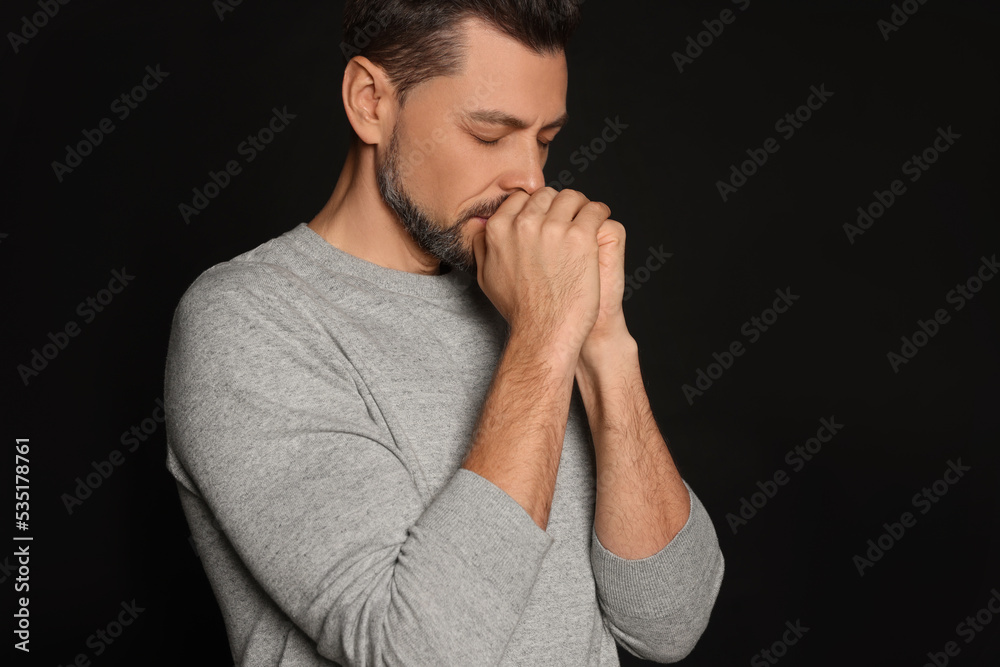 Man with clasped hands praying on black background Man with clasped hands praying on black background