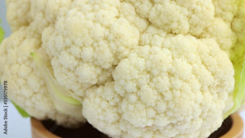 Whole head of the fresh raw cauliflower in wooden bowl. selective focus. Rotating on turn table. Whole head of the fresh raw cauliflower in wooden bowl. selective focus. Rotating on turn table.