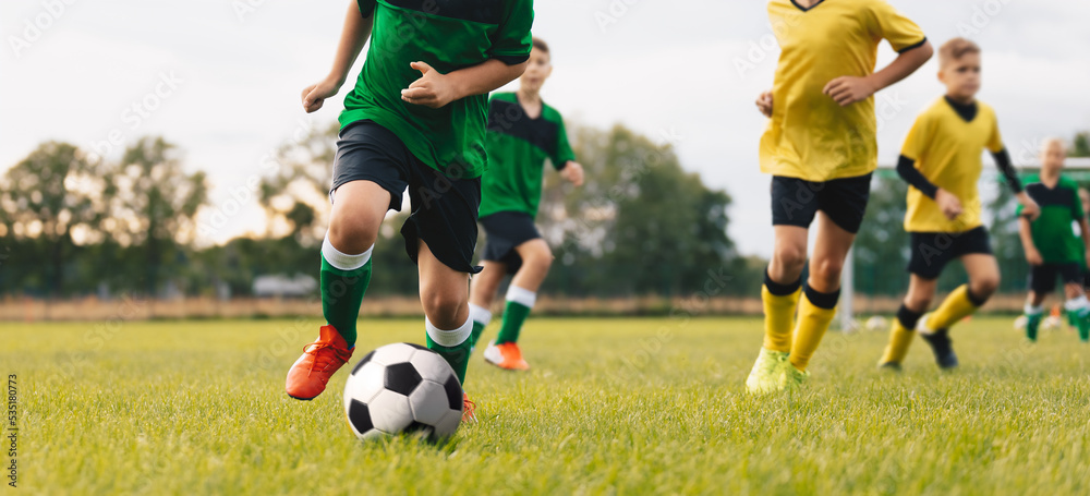 Competition between players running and kicking football ball. Young boys playing soccer game. Kids having fun in sport. Happy kids compete in football game. Running soccer players. Football school Competition between players running and kicking football ball. Young boys playing soccer game. Kids having fun in sport. Happy kids compete in football game. Running soccer players. Football school