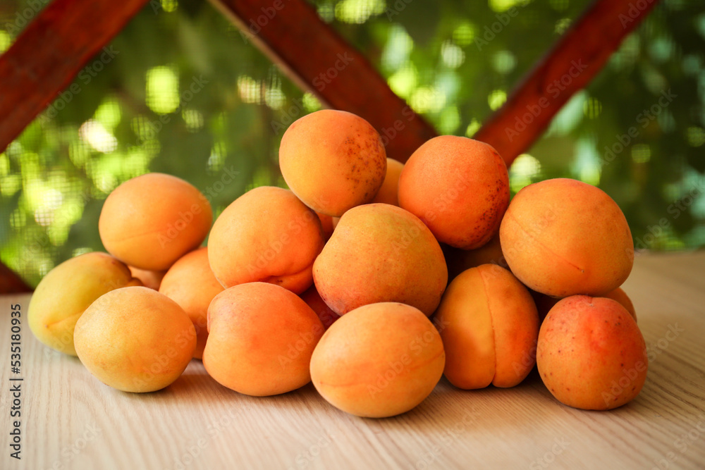 Heap of delicious ripe apricots on wooden table outdoors Heap of delicious ripe apricots on wooden table outdoors