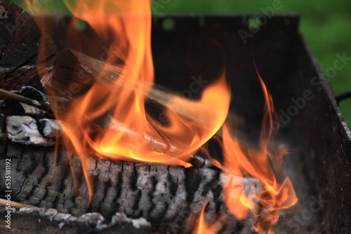 Metal brazier with burning firewood outdoors, closeup. Space or text