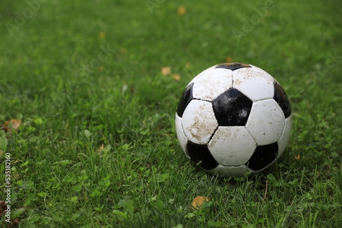 Dirty soccer ball on green grass outdoors  space for text