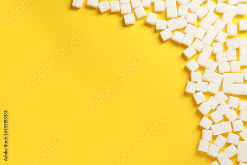 Foto White sugar cubes on yellow background, flat lay. Space for text