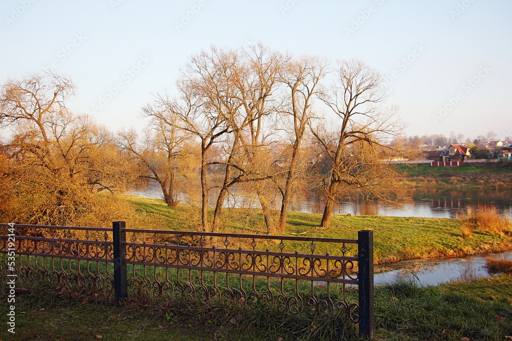 View of the river through the trees without foliage on an autumn sunny day. View of the river through the trees without foliage on an autumn sunny day.