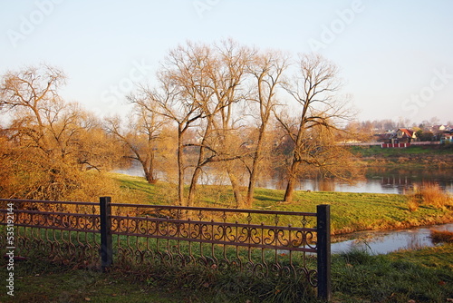 View of the river through the trees without foliage on an autumn sunny day.