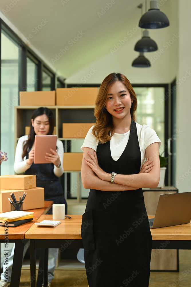 Portrait of small business owner in apron standing with arms crossed in modern home office